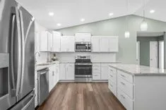 Modern kitchen interior with white cabinetry, stainless steel appliances, and granite countertops.