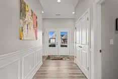 Modern hallway interior with double entry doors, decorative art on the wall, and wainscoting.