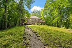Stone pathway leading to a house surrounded by lush greenery.