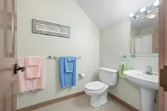 Small bathroom interior with a toilet, sink, and towels hanging on the wall.