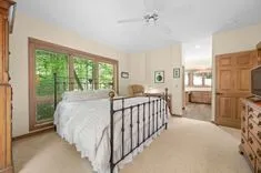Spacious bedroom with a large bed, wooden furniture, and a view of greenery through the window.