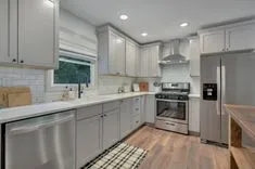 Modern kitchen interior with white cabinetry, stainless steel appliances, subway tile backsplash, and wood flooring.