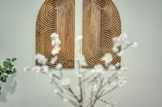 Wooden wall art with concentric circles hung behind a blurred foreground of white flowers.