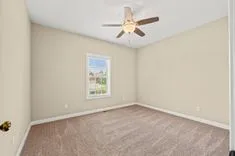 Empty room with beige walls, a window, and a ceiling fan.