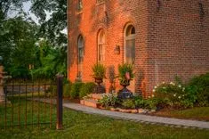 Brick house with arched windows adorned with flower pots and American flags at golden hour.
