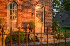 Traditional brick house entrance with American flags and sunset light casting warm glow on the door and windows.