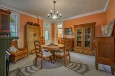 Elegant vintage dining room with orange walls, wooden furniture, and a chandelier.