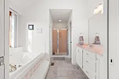 Modern bathroom interior with a white bathtub, double sink vanity, large mirror, and walk-in shower.
