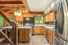 Spacious kitchen interior with wooden cabinetry, granite countertops, stainless steel appliances, and wood beam ceiling.