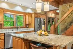 Warm and inviting kitchen interior with wooden cabinetry, granite countertops, modern appliances, and a rustic stone accent wall.