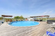 Outdoor swimming pool with surrounding wooden deck under a clear sky.