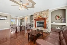Spacious living room with hardwood floors, a fireplace, leather sofa, and a ceiling fan.