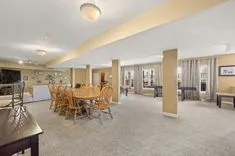 Spacious, well-lit basement with kitchen area, dining table, and multiple living spaces.