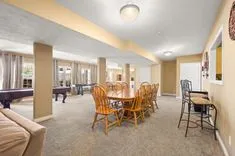 Spacious basement interior with dining area, pool table, and comfortable seating under warm lighting.
