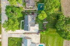Aerial view of a suburban home with a swimming pool and green backyard.