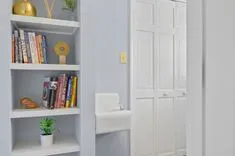 Cozy reading nook with a white bookshelf filled with books and decorative items next to a white door.