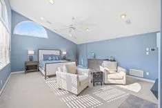 Bright spacious living room with blue walls, modern furniture, and large windows.