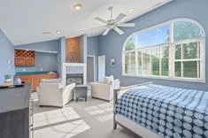 Spacious, modern bedroom with large windows, a fireplace, and blue decorative accents.