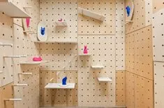 An indoor climbing wall designed for cats, featuring wooden shelves and wall steps against a pegboard background.