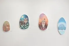 Four decorative Easter eggs with various patterns and illustrations displayed on a white wall.