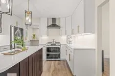Modern kitchen interior with white cabinets, stainless steel appliances, and hardwood floors.