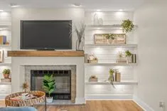 Cozy modern living room interior with mounted television above a fireplace, built-in shelving with decorative items, and comfortable seating area.