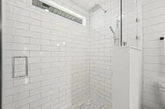 Modern bathroom with white subway tiles, glass shower door, and built-in niche for toiletries.