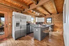 Rustic kitchen interior with wooden beams, stainless steel appliances, and a central island with stools.