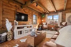 Cozy rustic living room interior with wood paneling, leather furniture, and a television mounted on the wall.