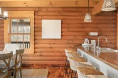 Cozy cabin kitchen interior with wooden walls, modern bar stools, and a framed abstract artwork.