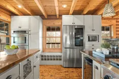 Rustic kitchen interior with stainless steel appliances, wood countertops, and wooden beams on the ceiling.