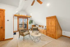 Bright and cozy attic living space with vaulted ceilings, wooden furniture, and a balcony.