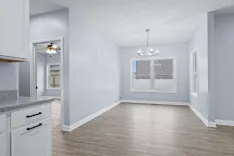 Empty living room interior with light blue walls, hardwood floors, and modern lighting fixtures.