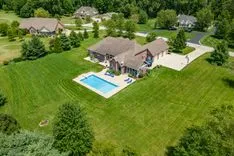 Aerial view of a suburban house with a large backyard and an outdoor swimming pool.
