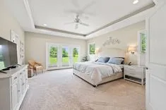 Spacious, well-lit bedroom with a large bed, ceiling fan, and French doors leading to the outside.