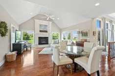 Bright and spacious living room with high ceilings, hardwood floors, fireplace, and dining area.