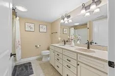 Modern bathroom interior with a shower curtain, vanity containing a sink with a large mirror, and flower-themed wall decor.