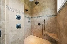Modern tiled walk-in shower with multiple shower heads and built-in bench.