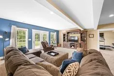 Spacious living room with vaulted ceiling, sectional sofa, entertainment unit, and French doors leading to exterior.