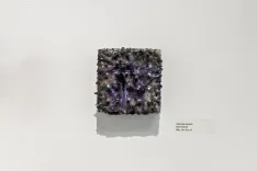 A cubic amethyst geode on display against a white background with a small descriptive label to the side.