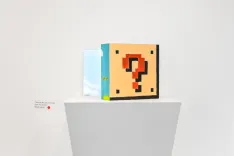 A question mark block from the Super Mario series on a pedestal, with a framed picture of a cloudy sky in the background.