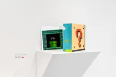 Two books with pixelated designs on a white shelf against a white background, with a minimalist aesthetic.