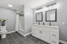 Modern bathroom interior with double sink vanity, mirrors, and a shower with white curtain.
