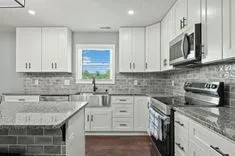 Modern kitchen interior with white cabinetry, granite countertops, and stainless steel appliances.