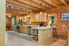 Interior of a cozy wooden cabin kitchen with modern appliances and a central island.