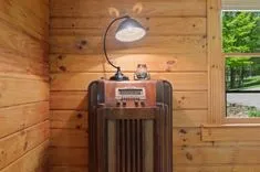Vintage radio and lamp on a wooden cabinet with a window showing greenery outside.