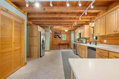 Interior of a rustic kitchen with wood cabinetry and exposed ceiling beams.