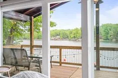 View from a covered patio with outdoor furniture overlooking a tranquil lake.