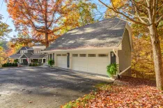 A picturesque suburban home with an attached garage surrounded by autumn foliage.