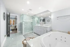 Spacious modern bathroom with double vanity, large mirror, glass-enclosed shower, and whirlpool tub.
